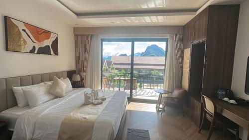 a hotel room with a bed and a large window at Sunset Mountain View Resort in Vang Vieng