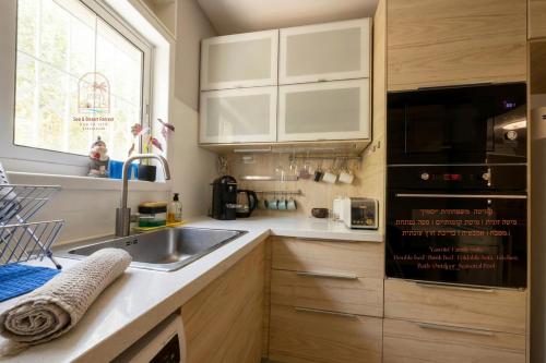 a kitchen with white cabinets and a sink and a window at Sea & Desert Retreat in Arad