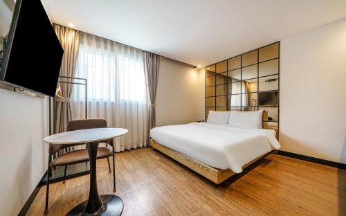 a hotel room with a bed and a table and a tv at 부산 연산동 MU Plus 호텔 in Kŏje
