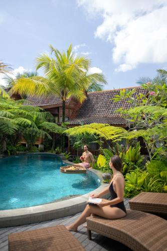 a woman sitting on a bench next to a swimming pool at Edge of Ubud by GenuineHost in Ubud