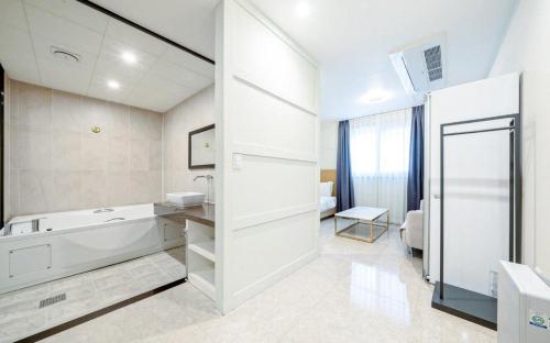 a white bathroom with a tub and a sink at 부산 연산동 MU Plus 호텔 in Kŏje