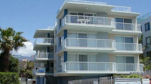 a tall building with white balconies and a palm tree at Spinnaker Seas Unit 2 in Caloundra