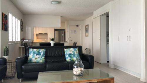 a living room with a black couch and a table at Spinnaker Seas Unit 2 in Caloundra