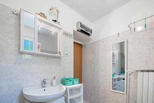 a white bathroom with a sink and a mirror at Apartment Gorgo in Sečovlje