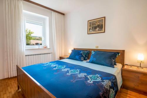 a bedroom with a bed with blue sheets and a window at Apartment Gorgo in Sečovlje