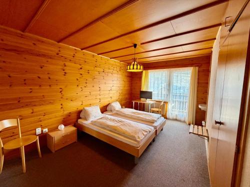a bedroom with two beds in a wooden wall at Hotel Gebidem in Visperterminen
