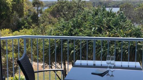 a table with two wine glasses on a balcony at Outlook Unit 7 in Kawana Waters