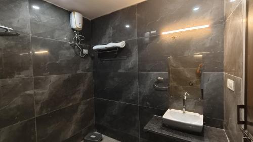 a black tiled bathroom with a sink and a mirror at Nal Village Resort By Explore With Nirav in Rupāwati