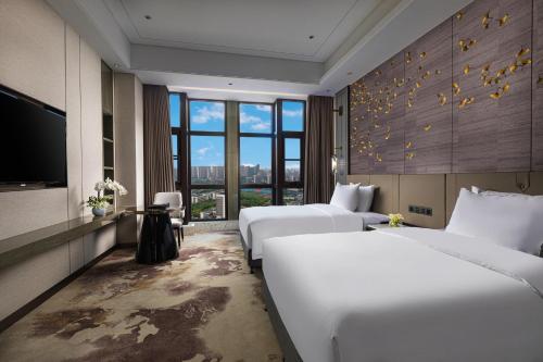 a hotel room with two beds and a flat screen tv at Wyndham Shanwei Haifeng in Shanwei