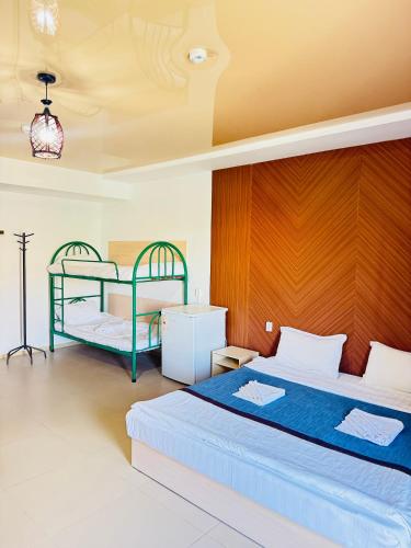 a bedroom with two beds and a wooden wall at Dostar Beach Hotel - Достар Жағажай Қонақүйі in Aktau