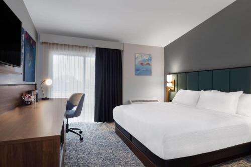 a hotel room with a large bed and a desk at Wingate by Wyndham Geneva at SPIRE Academy in Geneva