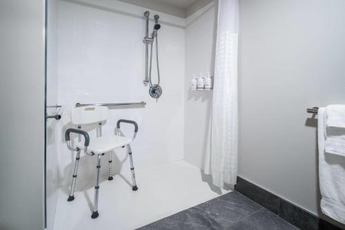 a white bathroom with a shower and a white chair at Wingate by Wyndham Geneva at SPIRE Academy in Geneva