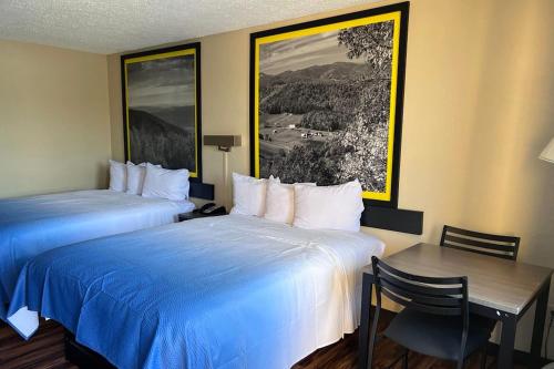 a hotel room with two beds and a table and a desk at Super 8 by Wyndham Lumberton NC in Lumberton