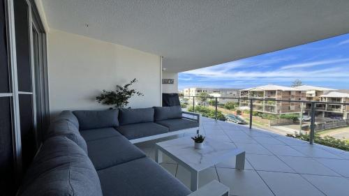 a living room with a blue couch and a balcony at Seabourn Unit 502 in Caloundra