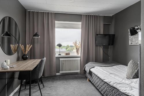 a bedroom with a bed and a desk and a window at Stora Hotellet Markaryd in Markaryd