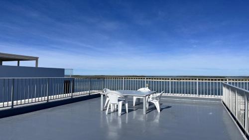 a table and chairs on a balcony with the ocean at Absolute Waterfront With Rooftop! in Caloundra