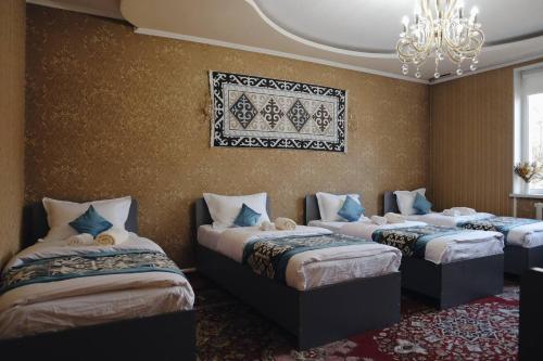 four beds in a room with a chandelier at Nomad Guest House Osh in Osh