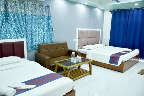 a hotel room with two beds and a chair at S S Plaza in mayapur