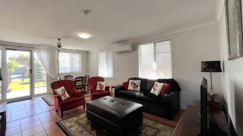 a living room with a black couch and red chairs at Drakes Hideaway in Golden Beach