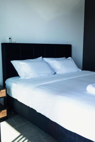 ein großes Bett mit weißen Laken und Kissen in der Unterkunft Rois Constructions in Nikosia