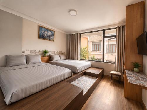 a hotel room with two beds and a television at Thiên Ngân Hostel in Da Lat