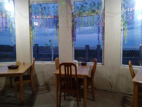 two tables and chairs in a room with windows at Кафе Кочевник in Chon-Sary-Oy
