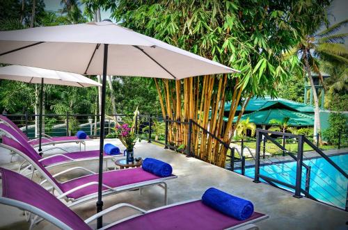 a group of purple chairs and an umbrella next to a pool at The Kings Villa in Kandy