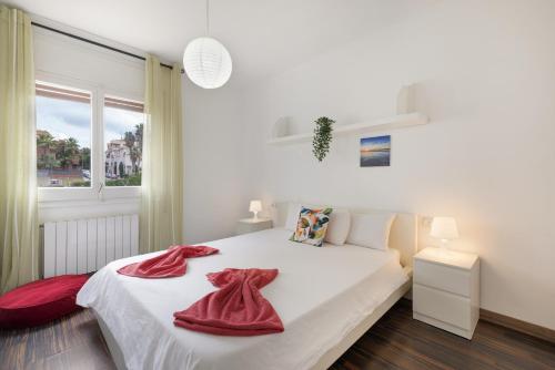 ein Schlafzimmer mit einem weißen Bett mit roten Handtüchern darauf in der Unterkunft Melody in Sitges