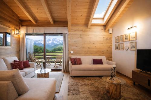 a living room with couches and a television and mountains at SKYWAY LOFT - Residence Veronza con piscina, Dolomiti Affitti in Cavalese