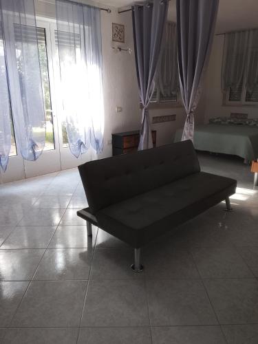 a black couch sitting in a room with windows at La casetta in Martina Franca