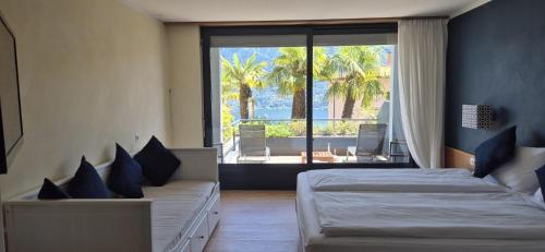 a bedroom with two beds and a large window at Hotel Barca Blu in Orselina