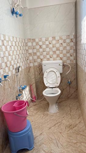 a bathroom with a toilet and a bucket in it at Kanak Bihari Enclave in Ayodhya