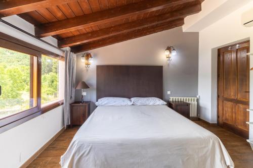 a bedroom with a large white bed and windows at Casa Viria in Navaluenga