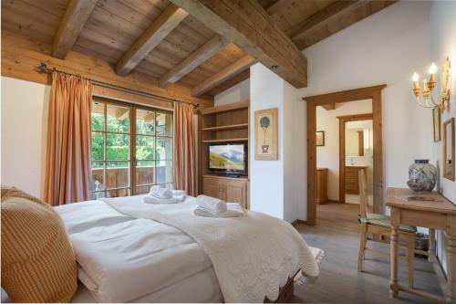 a bedroom with a large white bed and a table at Chalet Lebenberg Kitzbühel in Kitzbühel