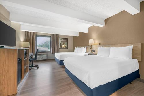a hotel room with two beds and a flat screen tv at Fairway Inn and Suites, an Ascend Collection Hotel in Mishicot