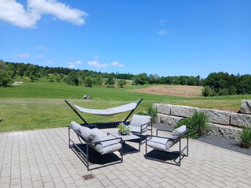a couple of chairs and a hammock on a patio at Ferienwohnung Waldlichtung in Simmersfeld