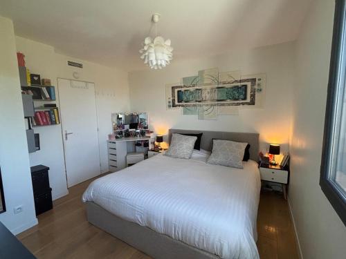a bedroom with a white bed and a chandelier at La Maison Bernard in Roquefort-la-Bédoule