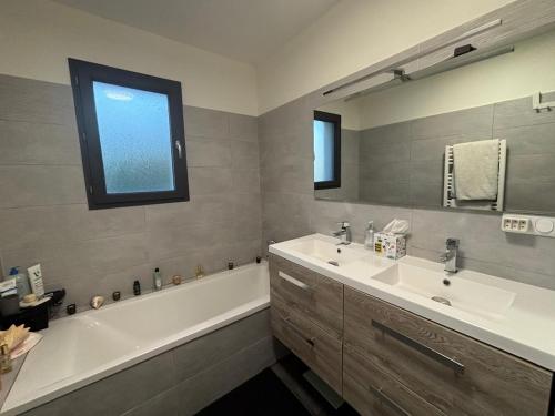 a bathroom with a tub and a sink and a tub and a mirror at La Maison Bernard in Roquefort-la-Bédoule
