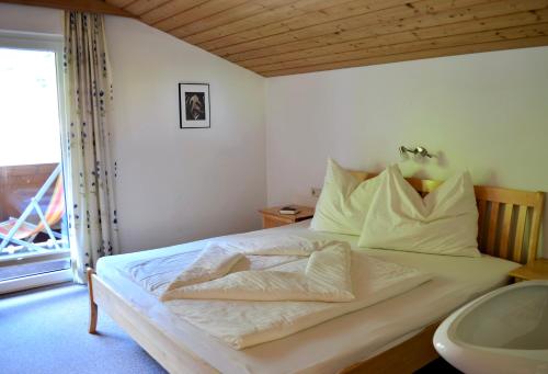 a bedroom with a bed with white sheets and a window at Haus Hofer in Bramberg am Wildkogel