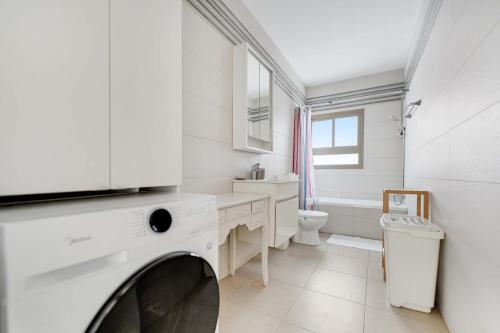 a white bathroom with a washing machine in it at Spacious Sea-View Penthouse + Big Balconies in Ashdod