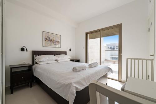 a bedroom with a bed with white sheets and a window at Spacious Sea-View Penthouse + Big Balconies in Ashdod