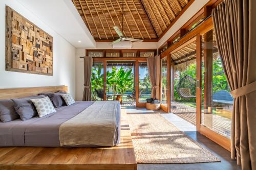 a bedroom with a bed and sliding glass doors at La Reserva Villas Bali in Jimbaran
