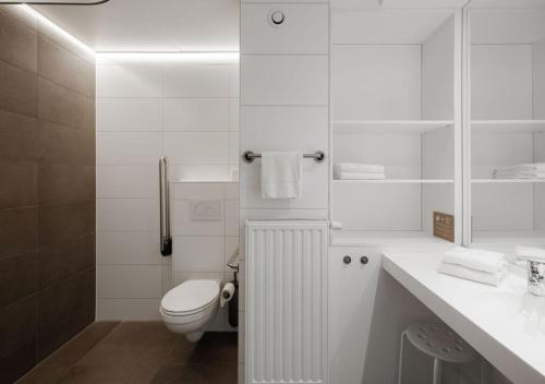 a white bathroom with a toilet and a sink at Duindomein Ter Helme in Oostduinkerke