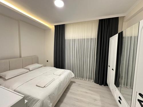 a bedroom with a white bed and a large window at Ak Suites Rezidans in Trabzon