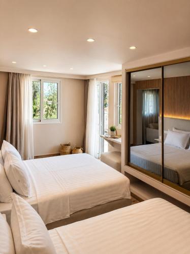 ein Schlafzimmer mit zwei Betten und einem großen Spiegel in der Unterkunft Eva Beach Hotel Lefkada in Nydri