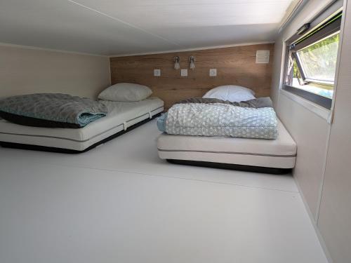 two beds are sitting in a room in a trailer at Tiny house in Saint-Côme-dʼOlt