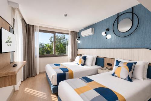 a hotel room with two beds and a television at Mesona Hotels Blue Hill in Antalya