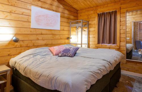 a bed in a room with wooden walls at Familie Resort de Tovertuin in Hoogerheide