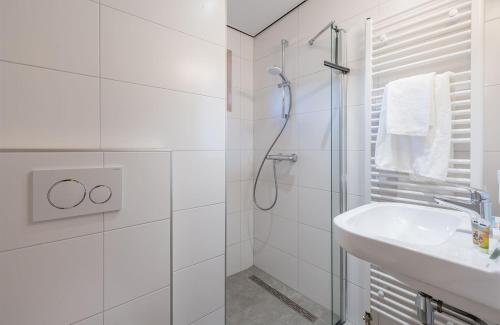a white bathroom with a shower and a sink at Familie Resort de Tovertuin in Hoogerheide