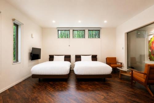 two beds in a room with wooden floors and windows at Comlien Villa Resort in Tateyama